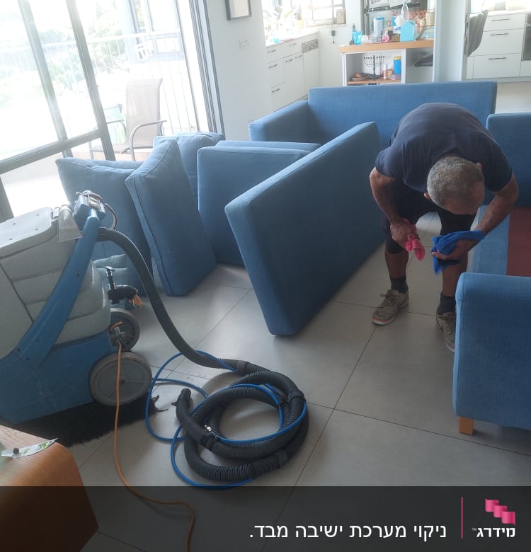 אדם מנקה ספה עם מכונת ניקוי ושואב אבק